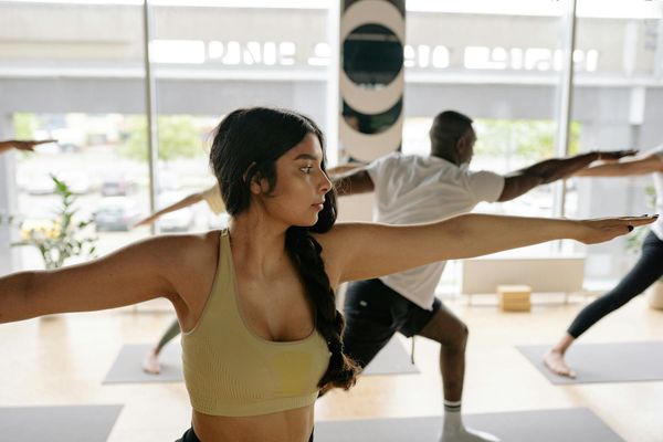 Woman in a flowing yoga warrior pose in a bright room.